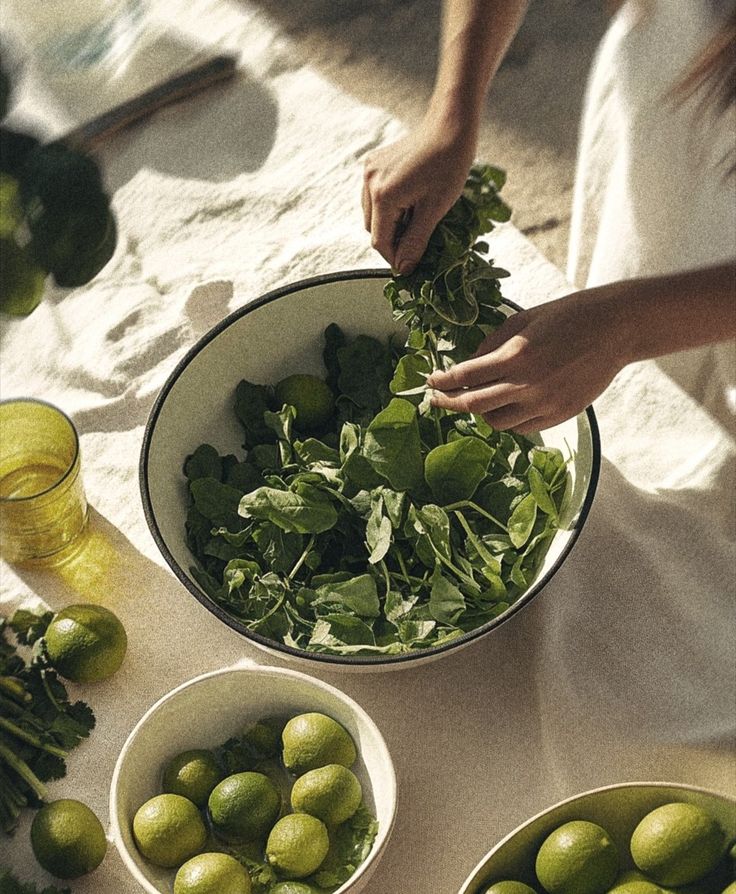 Hands preparing a fresh green salad with limes